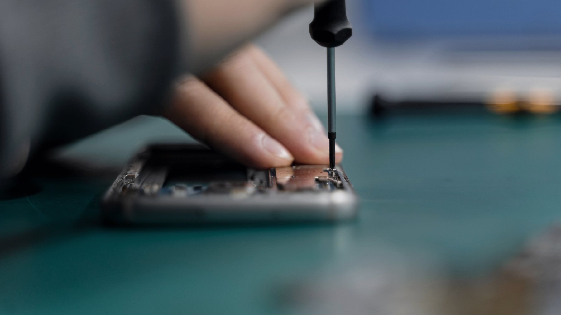 Technik precyzyjnie naprawiający smartfon na profesjonalnym stanowisku serwisowym